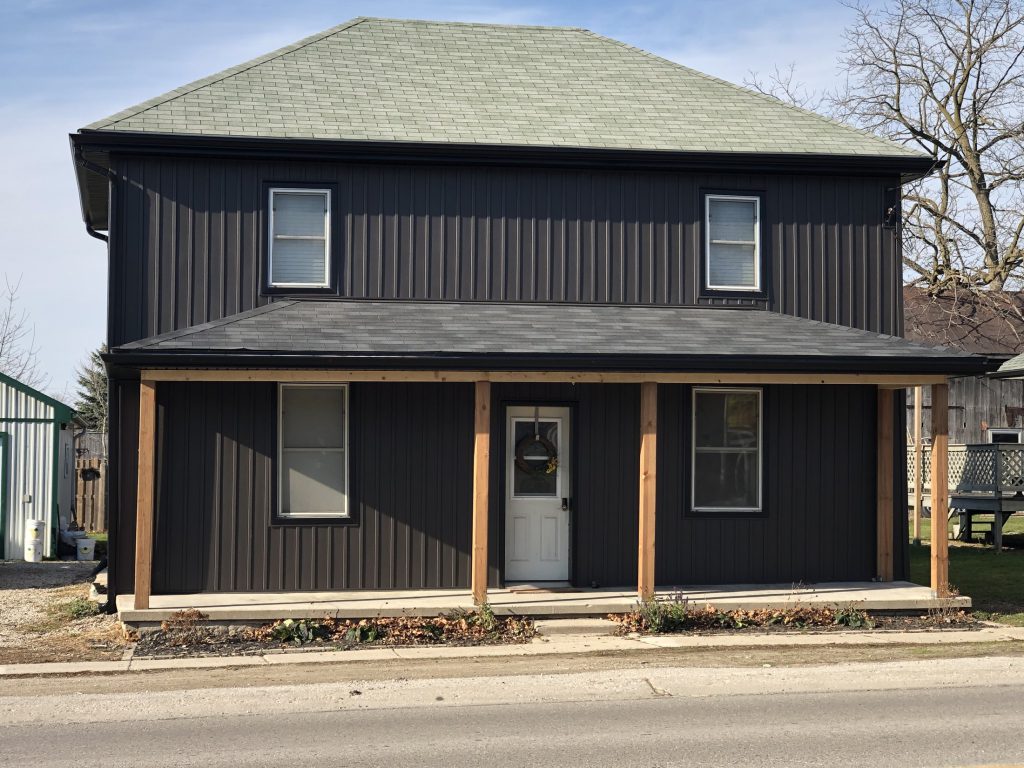 Finished residential exterior with dark siding and covered front porch