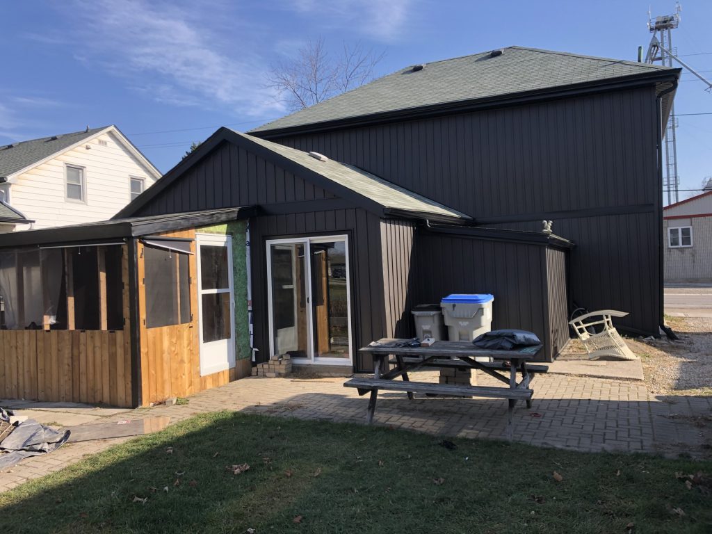 Rear exterior with new dark siding and timber entry