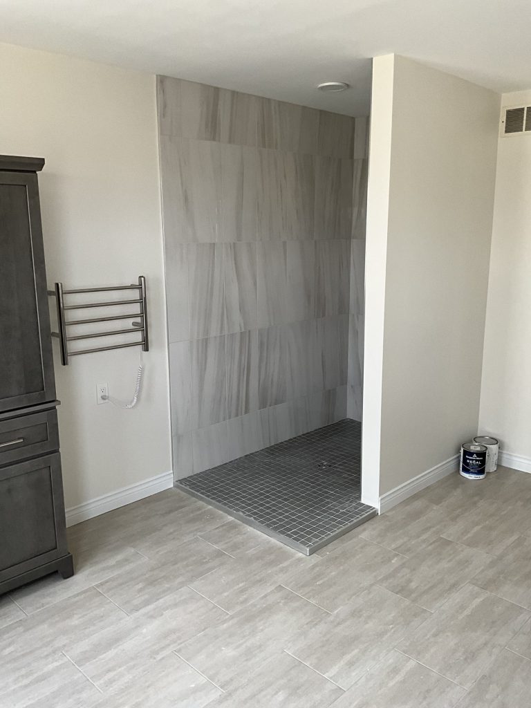 Tiled shower and linen cabinet in the renovated bathroom